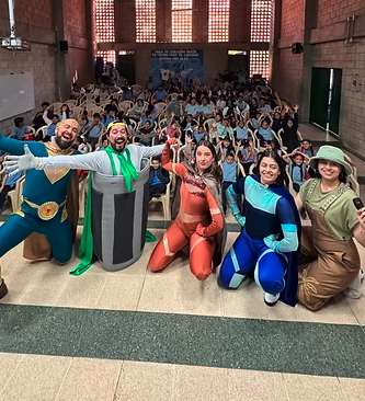 Voluntarios de la Liga vestidos como los personajes, junto a niños en un auditorio